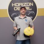 Owner of Horizon Detail in front of logo holding polisher and polish with a polish smiley face on the polisher pad