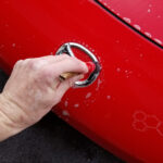 2008 Mazda Miata in for paint correction and ceramic coating decon wash mazda emblem being brushed out close up